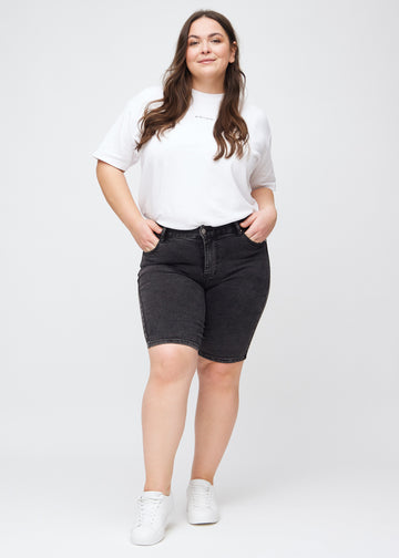 Fullt bilde av en plus-size modell i mørkegrå denim skinny middle shorts.