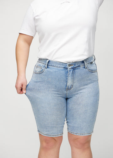 Plus-size-modellen strekker shortsen ved låret for å vise stretch.