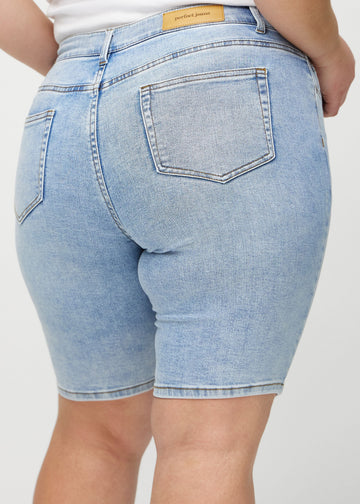 Lys denim skinny middle shorts sett bakfra på nært hold på en plus-size-modell for å vise detaljer.