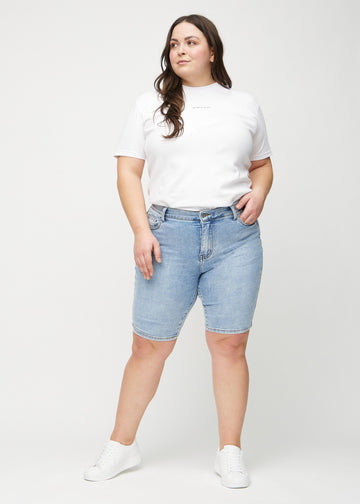 Fullt bilde av en plus-size-modell i lys denim skinny middle shorts.