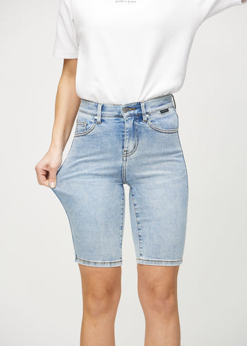 Modellen strekker shortsen ved låret for å vise stretch.
