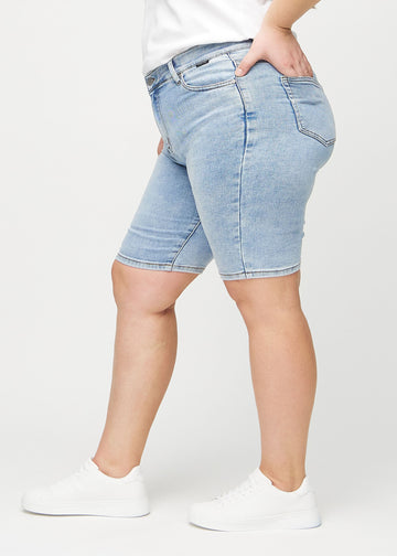 Lys denim skinny middle shorts sett fra siden på en plus-size-modell.