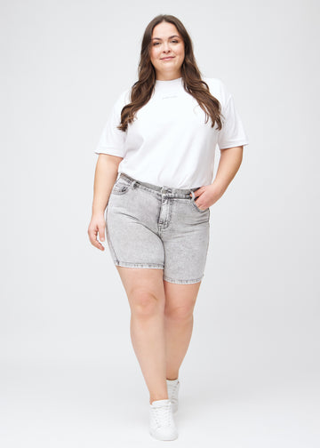 Fullt bilde av en plus-size modell i lysgrå denim skinny short shorts.