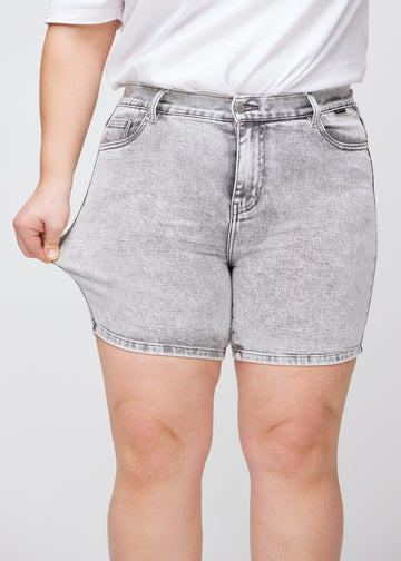 Plus-size modell strekker shortsene ved låret for å vise stretch.