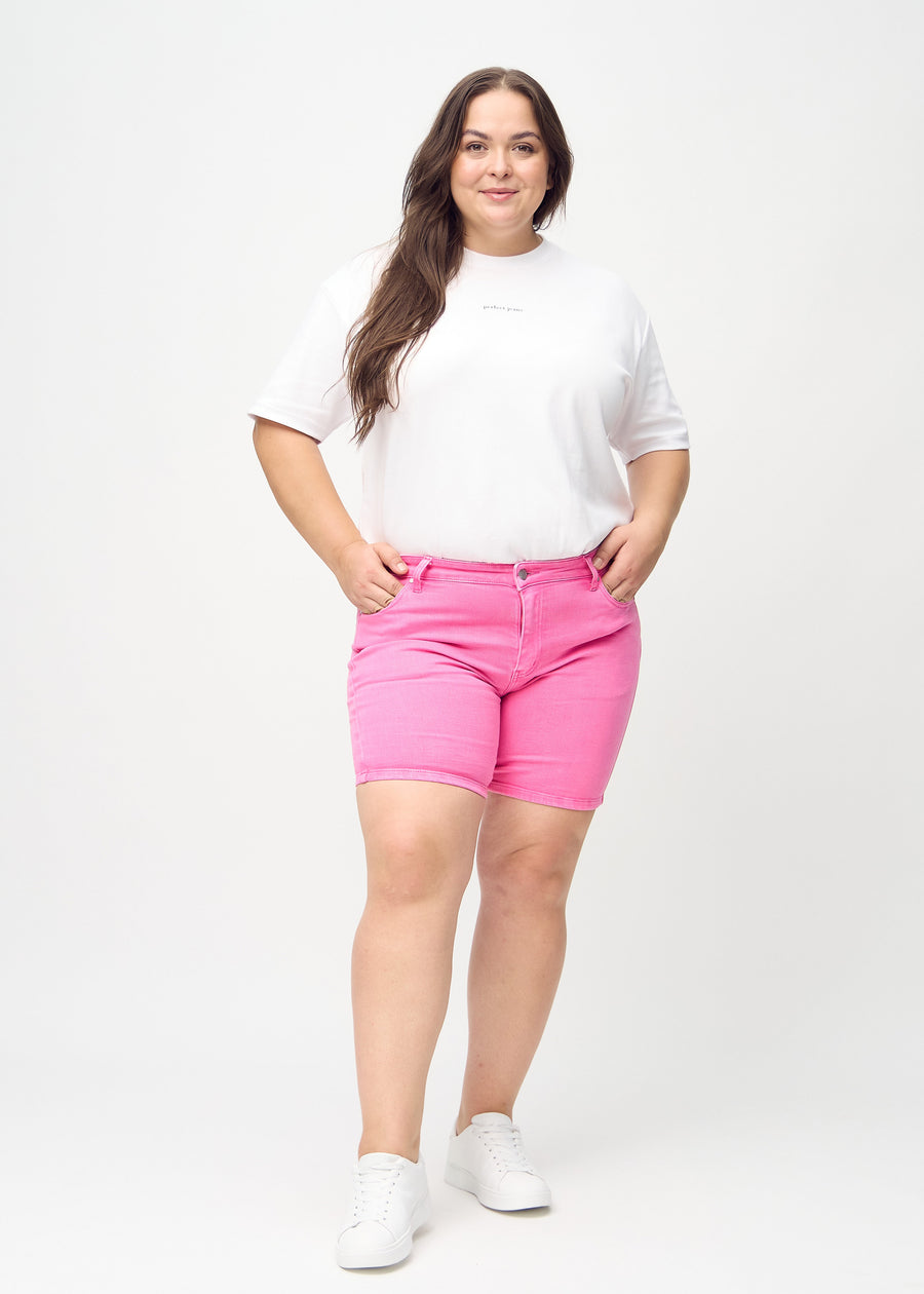 Fullt bilde av en plus-size-modell i lyserosa skinny short shorts.