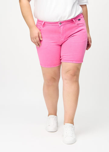 Lyserosa skinny short shorts, modellnavn Flamingos, som sitter tett på og slutter midt på låret på en plus-size-modell, sett forfra.