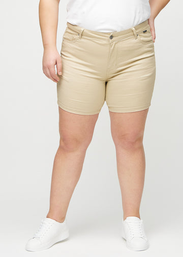 Beige skinny short shorts, modellnavn Gazelles, som sitter tett og slutter midt på låret på en plus-size-modell, sett forfra.