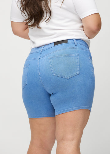 Blå skinny short shorts sett bakfra på nært hold på en plus-size-modell for å vise detaljer.