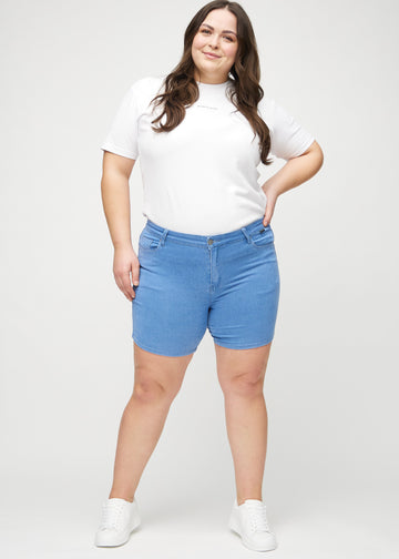 Fullt bilde av en plus-size-modell i blå skinny short shorts.