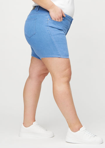 Blå skinny short shorts sett fra siden på en plus-size-modell.