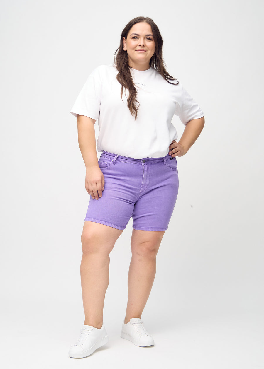 Fullt bilde av en plus-size modell i lilla skinny short shorts.