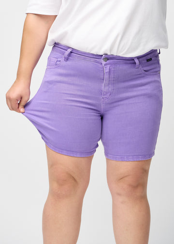 Plus-size modellen strekker shortsen ved låret for å vise stretch.