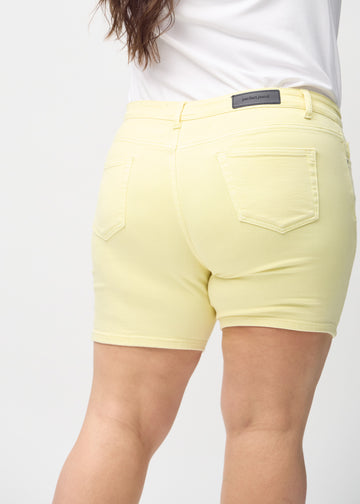 Lysegule skinny short shorts sett bakfra på nært hold på en plus-size-modell for å vise detaljer.