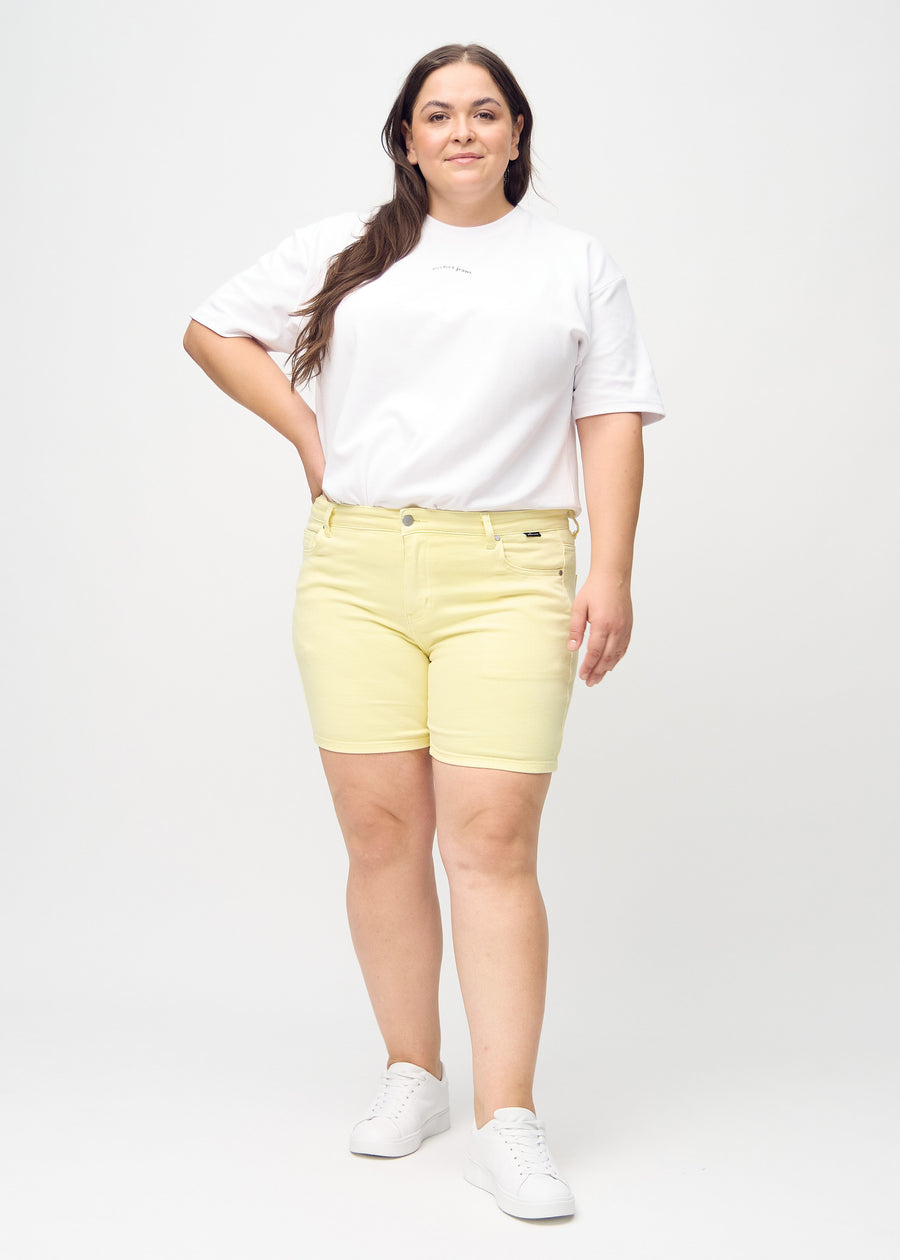 Fullt bilde av en plus-size-modell i lysegule skinny short shorts.