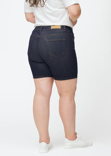 Dyp mørkeblå denimshorts til dame i fargen Midnights sett bakfra på plus-size modell, slik at lengden til midt på låret vises.