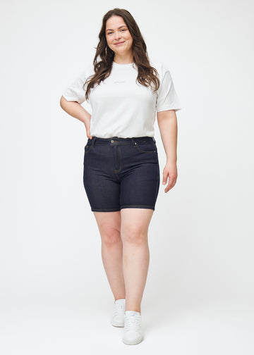 Helbilde av plus-size modell i dyp mørkeblå denimshorts til dame i fargen Midnights med skinny passform.