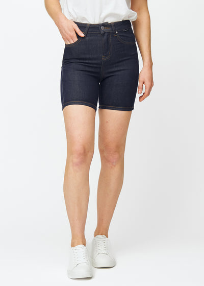 Dyp mørkeblå denimshorts til dame i fargen Midnights med skinny passform som sitter tett ved hoften og følger lårene, sett forfra.
