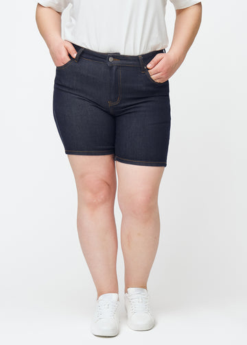 Dyp mørkeblå denimshorts til dame i fargen Midnights med skinny passform sett forfra på plus-size modell.
