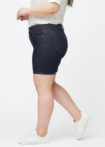 Dyp mørkeblå denimshorts til dame i fargen Midnights med skinny passform sett fra siden på plus-size modell.