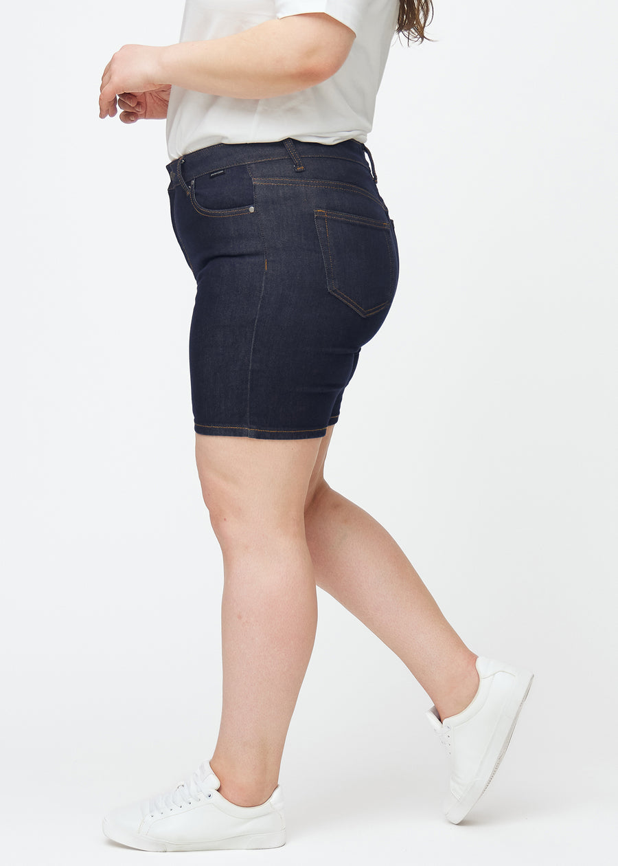 Dyp mørkeblå denimshorts til dame i fargen Midnights med skinny passform sett fra siden på plus-size modell.