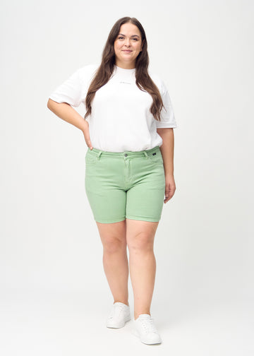 Fullt bilde av en plus-size-modell i lysegrønne skinny short shorts.
