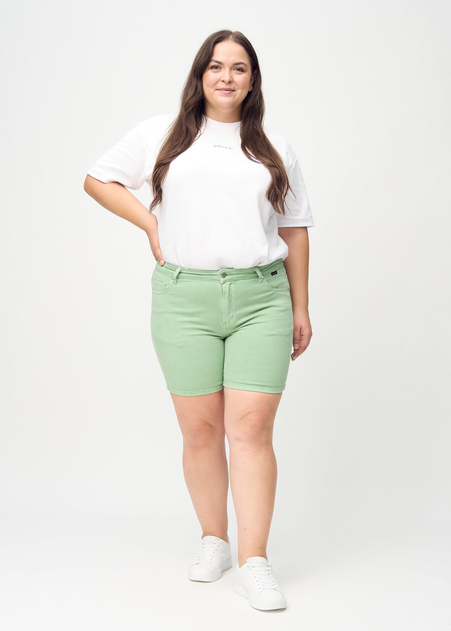 Fullt bilde av en plus-size-modell i lysegrønne skinny short shorts.