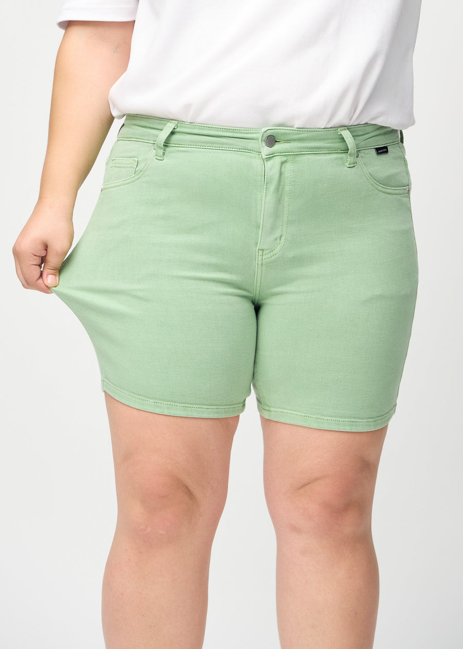Plus-size-modellen strekker shortsen ved låret for å vise stretch.