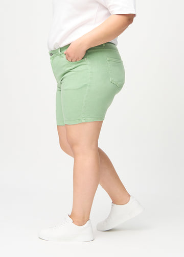 Lysegrønne skinny short shorts sett fra siden på en plus-size-modell.