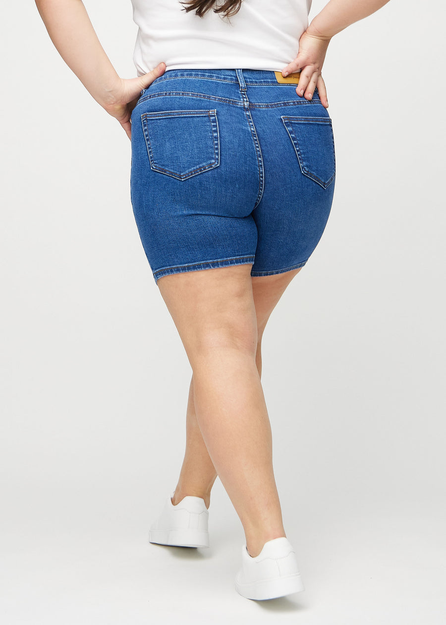 Mørk denim skinny short shorts sett bakfra på en plus-size-modell, slik at man kan se hele produktet.