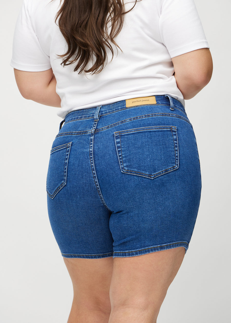 Mørk denim skinny short shorts sett bakfra på nært hold på en plus-size-modell for å vise detaljer.