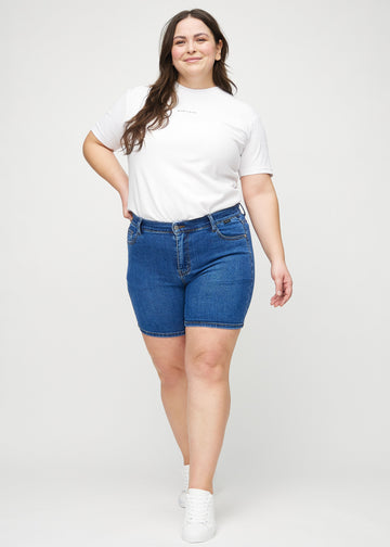 Fullt bilde av en plus-size-modell i mørk denim skinny short shorts.