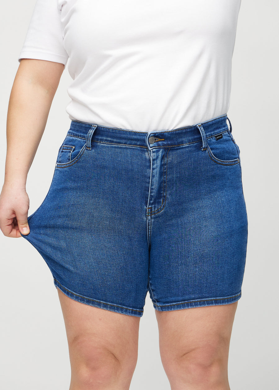 Plus-size-modellen strekker shortsene ved låret for å vise stretch.