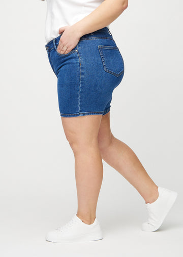 Mørk denim skinny short shorts sett fra siden på en plus-size-modell.
