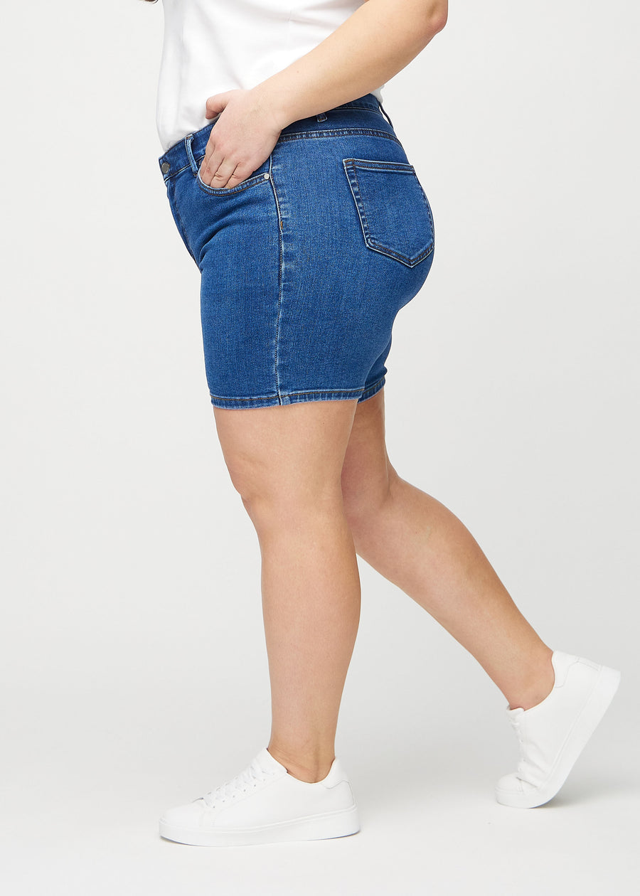 Mørk denim skinny short shorts sett fra siden på en plus-size-modell.