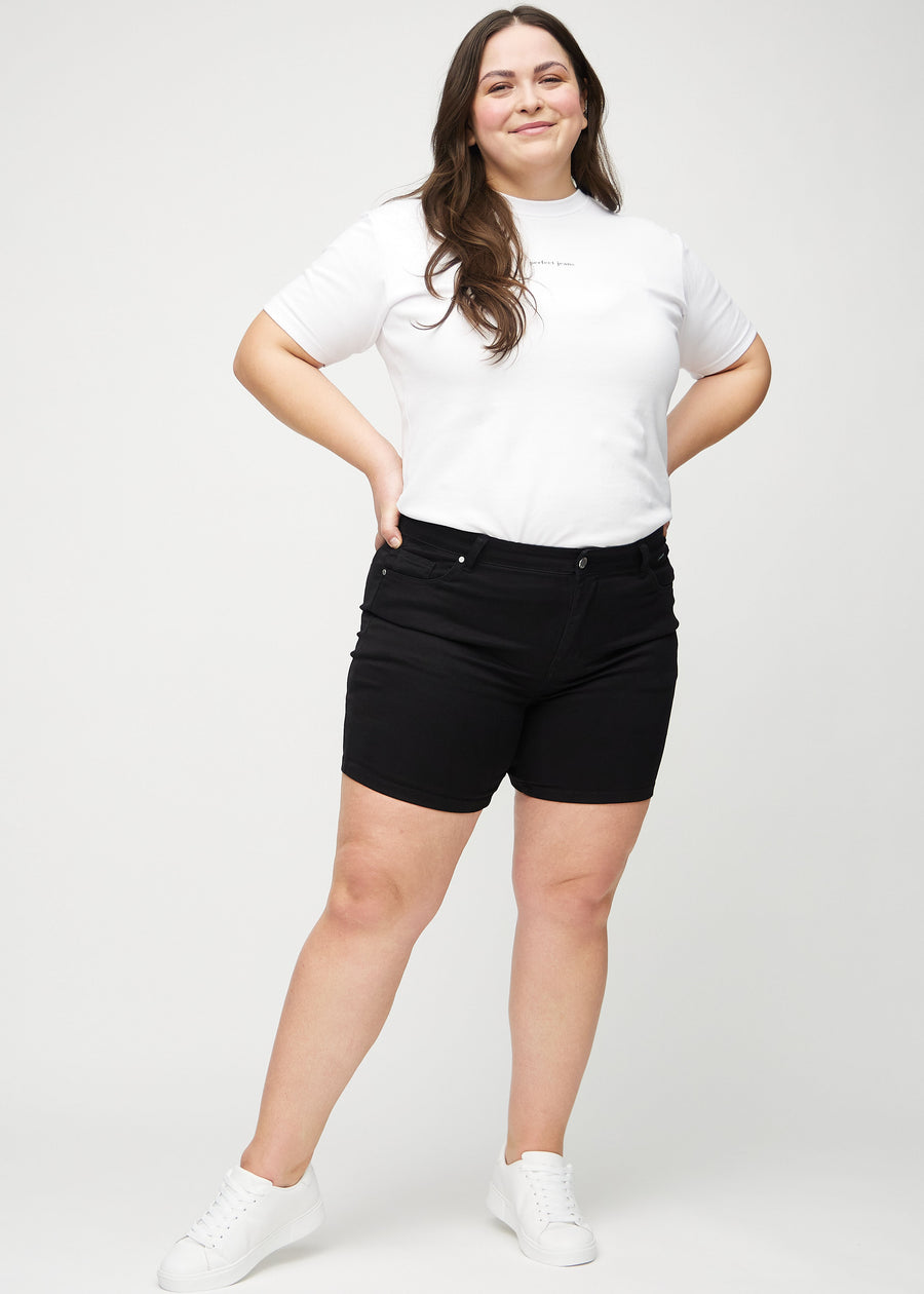 Fullt bilde av en plus-size-modell i svarte skinny short shorts.