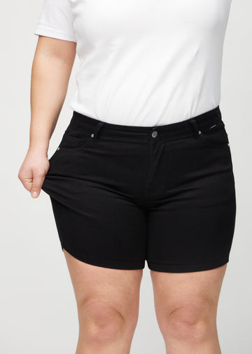 Plus-size-modellen strekker shortsene ved låret for å vise stretch.