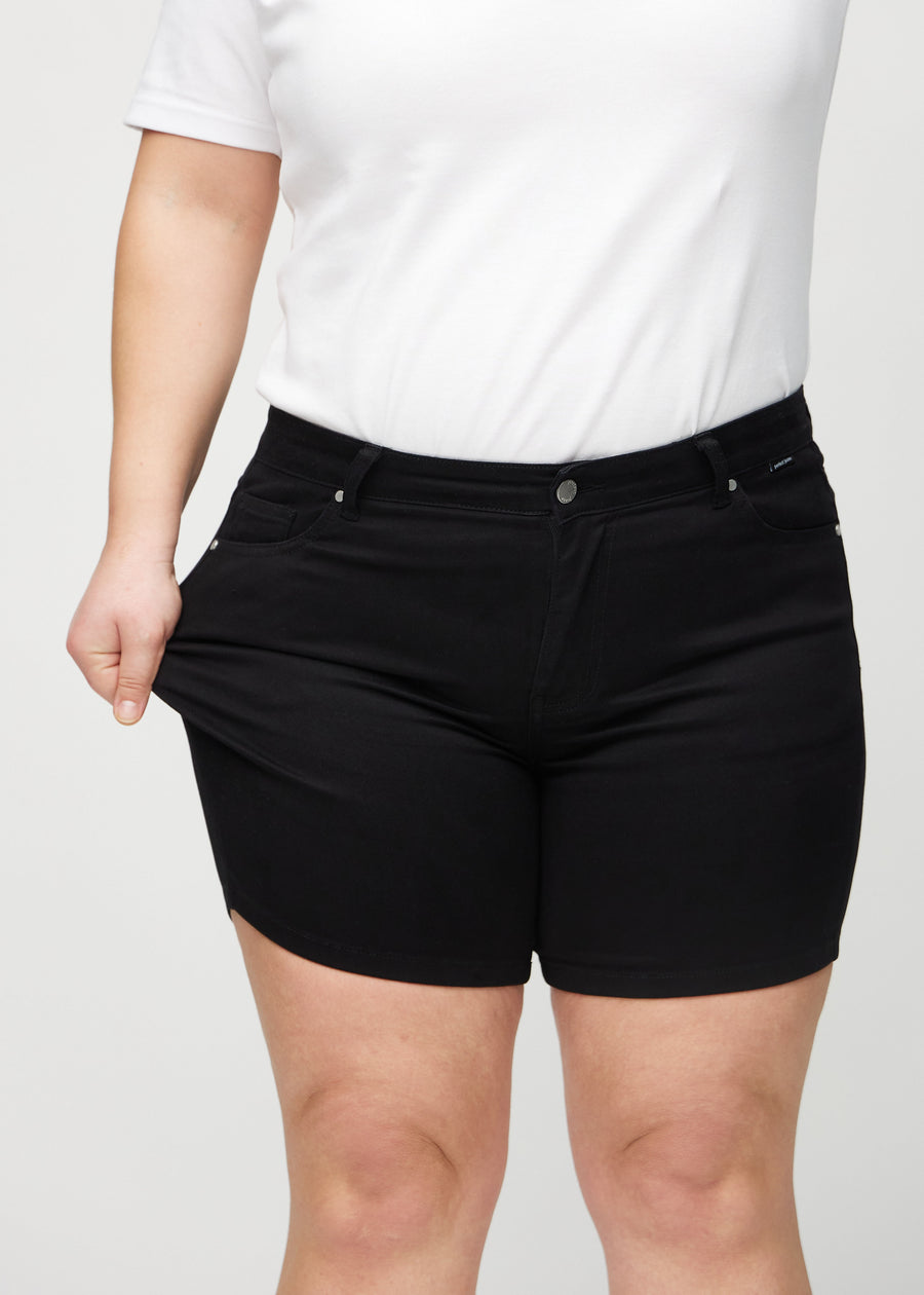 Plus-size-modellen strekker shortsene ved låret for å vise stretch.