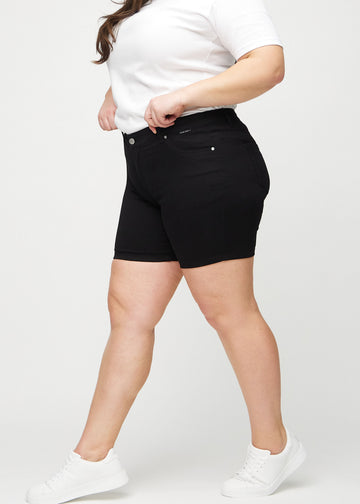 Svarte skinny short shorts sett fra siden på en plus-size-modell.