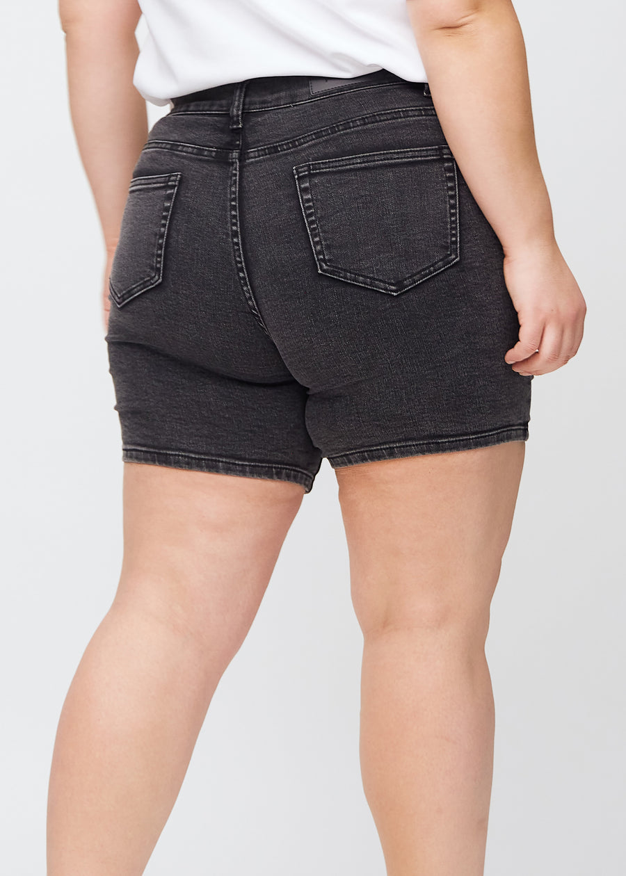 Mørkegrå denim skinny short shorts sett bakfra på nært hold på en plus-size-modell for å vise detaljer.