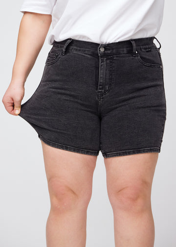 Plus-size-modellen strekker shortsene ved låret for å vise stretch.