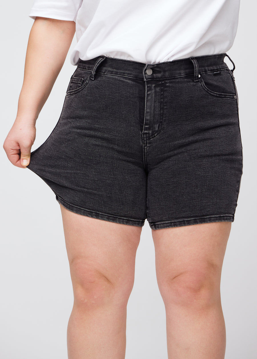 Plus-size-modellen strekker shortsene ved låret for å vise stretch.