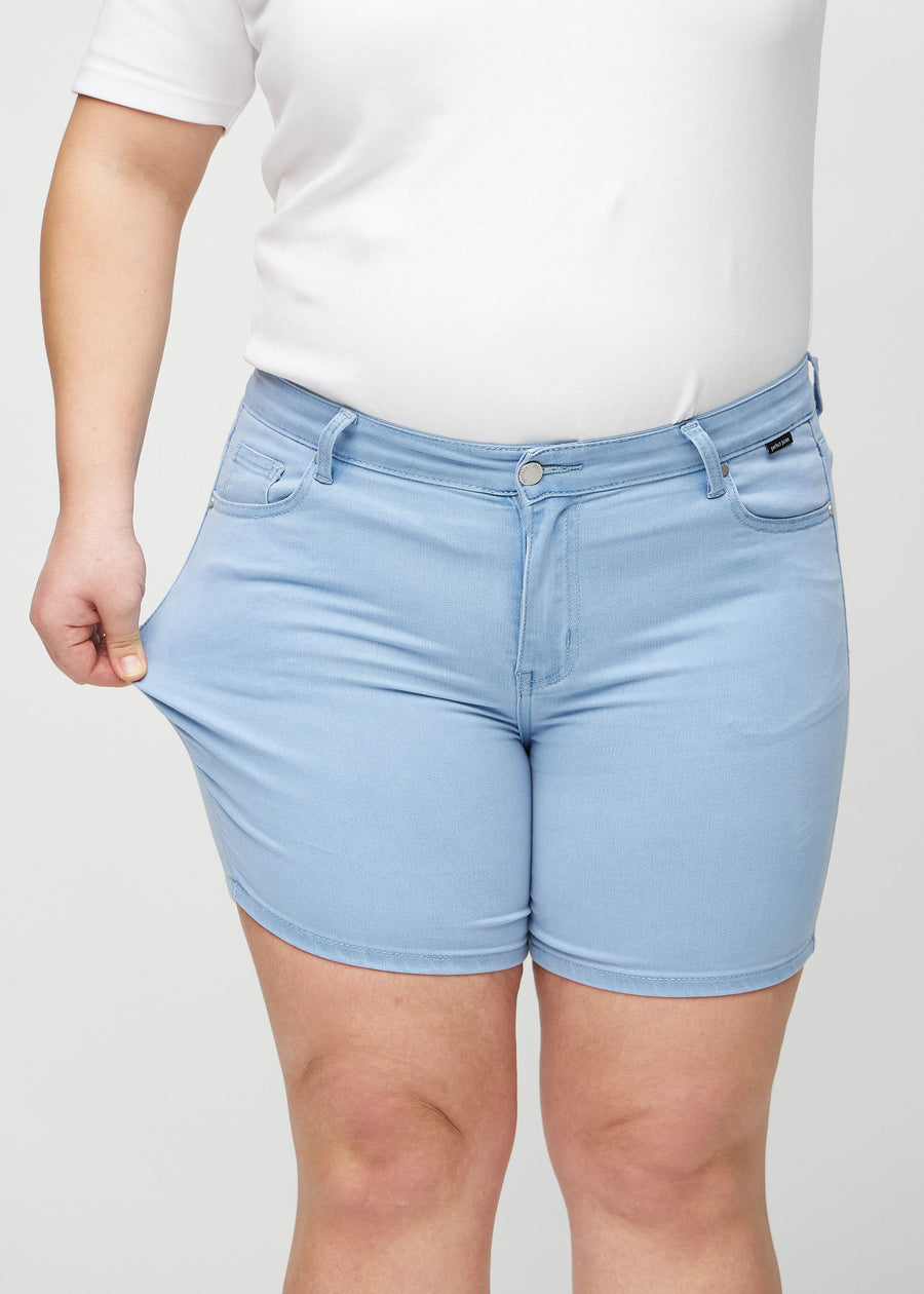 Plus-size-modellen strekker shortsene ved låret for å vise stretch.