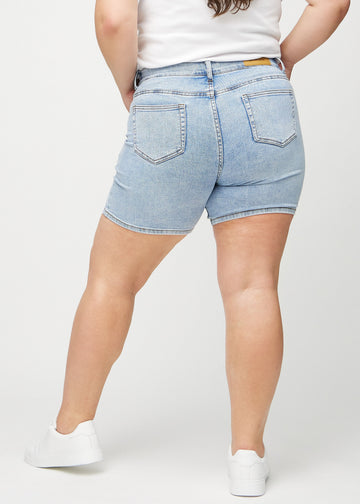 Lys denim skinny short shorts sett bakfra på en plus-size modell, slik at man kan se hele produktet.