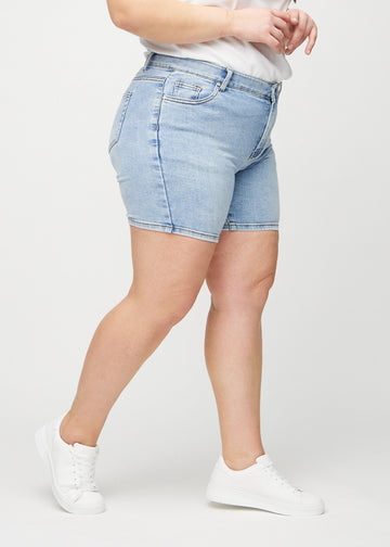 Lys denim skinny short shorts sett fra siden på en plus-size modell.