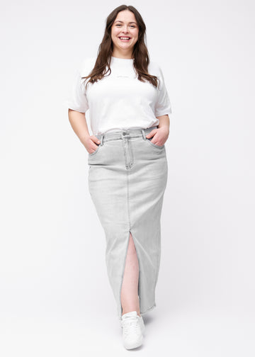 Langt lysegrått denimskjørt til kvinner i fargen Ashes. Helhetsbilde av en plus size-modell med skjørtet og splitten foran.
