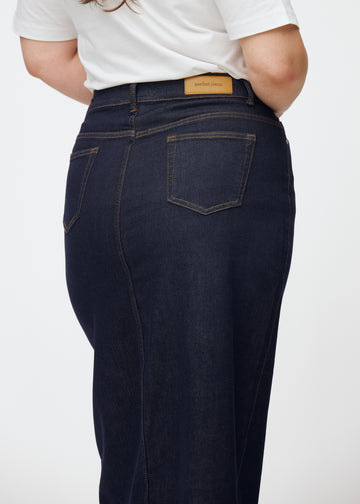 Langt dyp mørkeblått denimskjørt til dame i fargen Midnights sett bakfra i nærbilde på plus-size modell for å vise passform og detaljer.