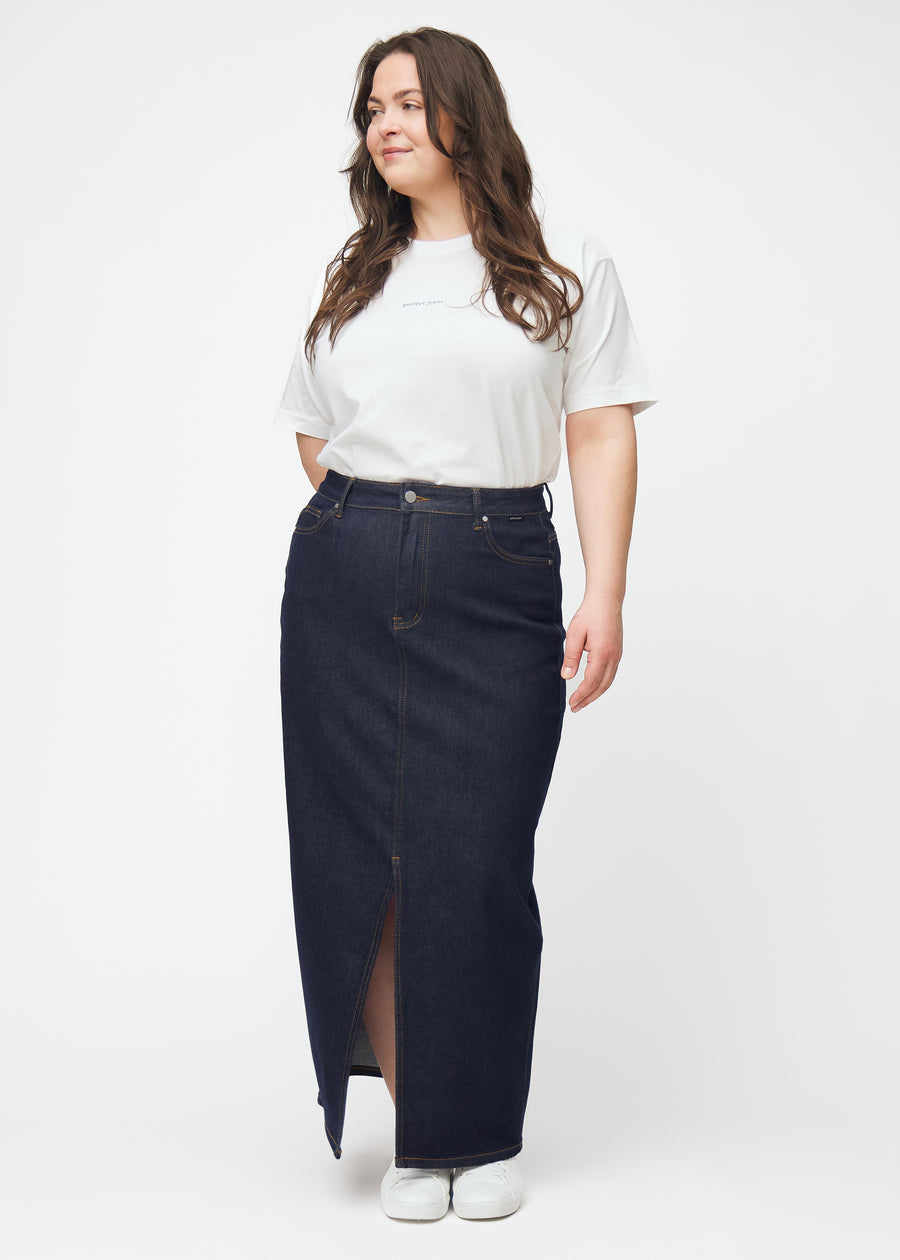 Helbilde av plus-size modell i langt dyp mørkeblått denimskjørt til dame i fargen Midnights med splitt foran.