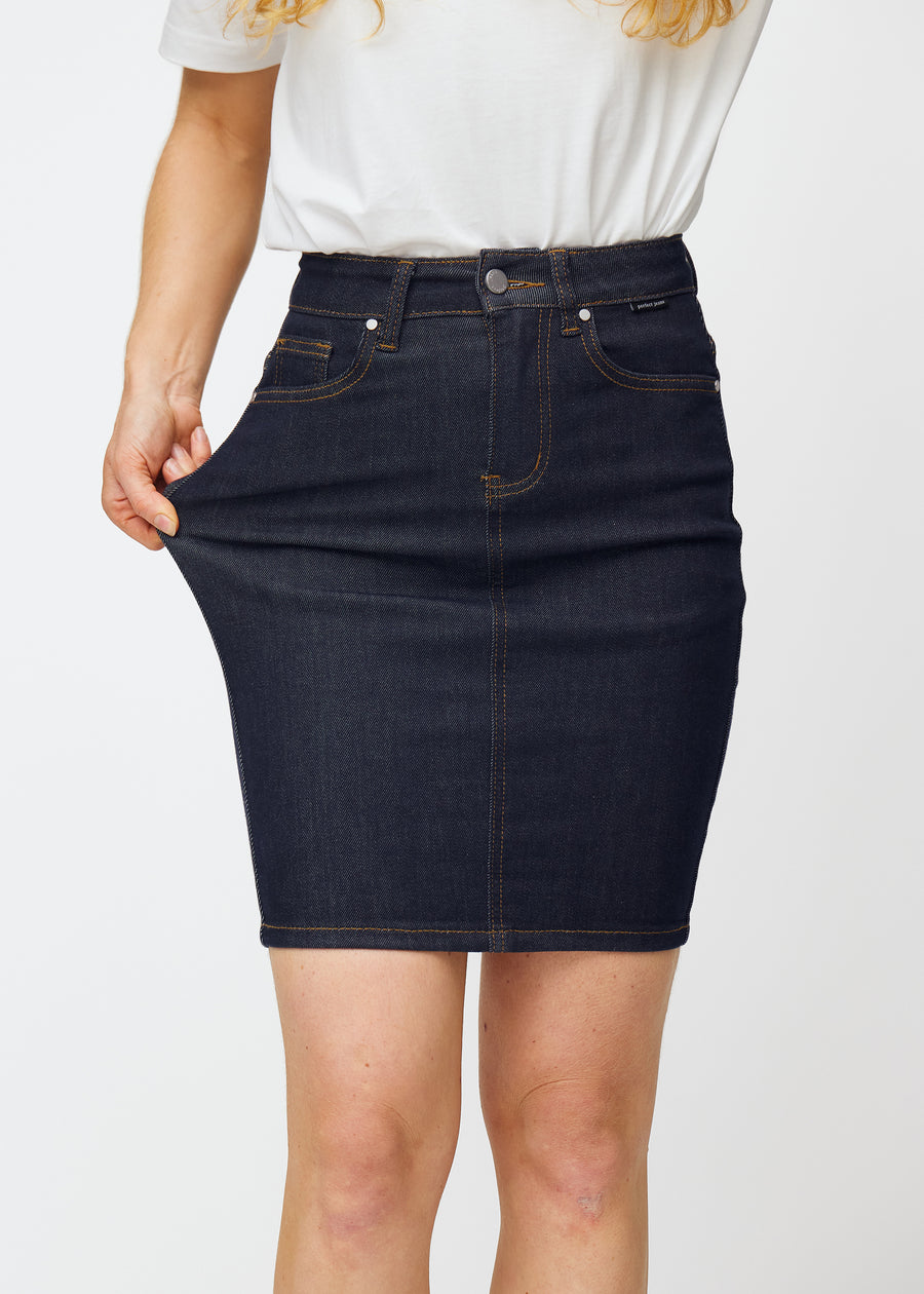 Modell strekker dyp mørkeblå denimskjørt til dame i fargen Midnights ved låret for å vise materialets stretch.