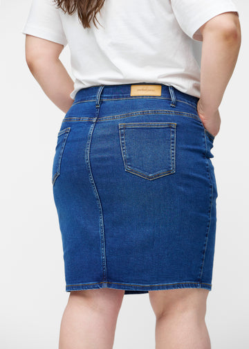 Mørkeblå, tætsiddende og knælang denimnederdel set bagfra tæt på på plus-size model for at vise detaljer.