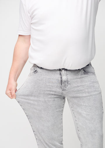 Plus-size-modellen strekker jeansene ved låret for å vise stretch.